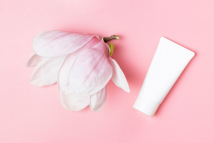 Tubo branco e flor de magnólia em fundo rosa