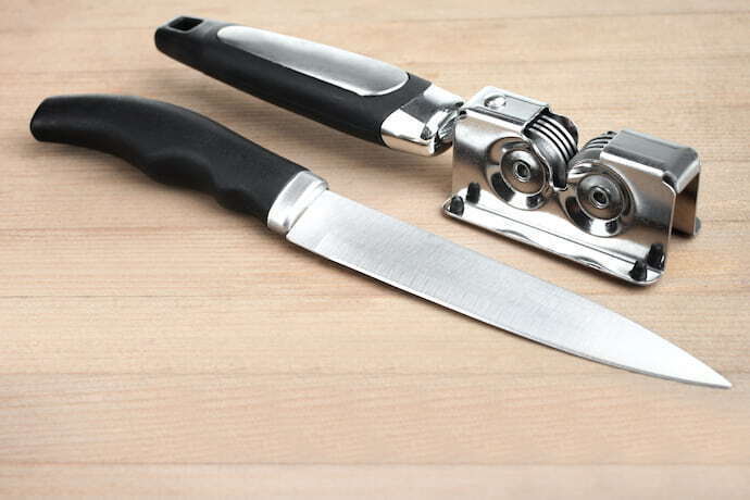 Amolador de faca preto e faca ao lado.