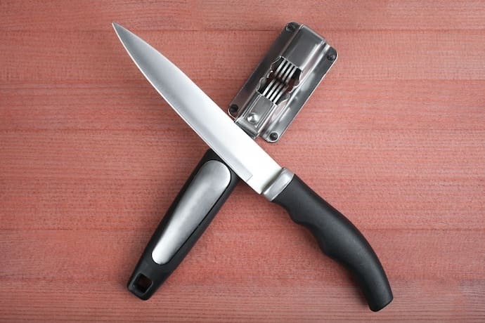 Amolador de faca e faca em cima de mesa.