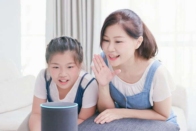 Mãe e filha interagindo com smart speaker.