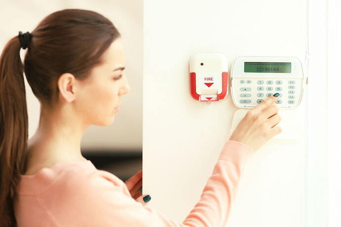 Mulher loira ajustando alarme residencial.