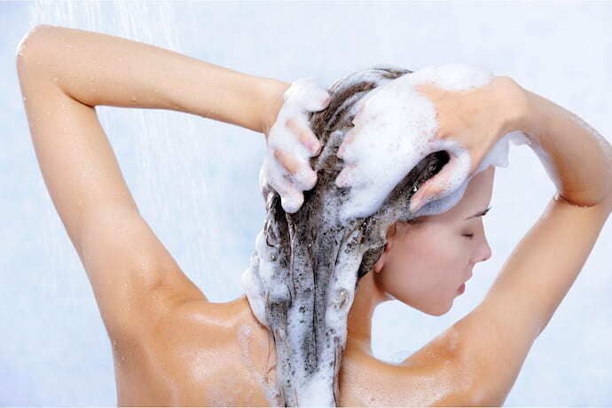 Mulher com cabelo cheio de espuma de shampoo em barra.