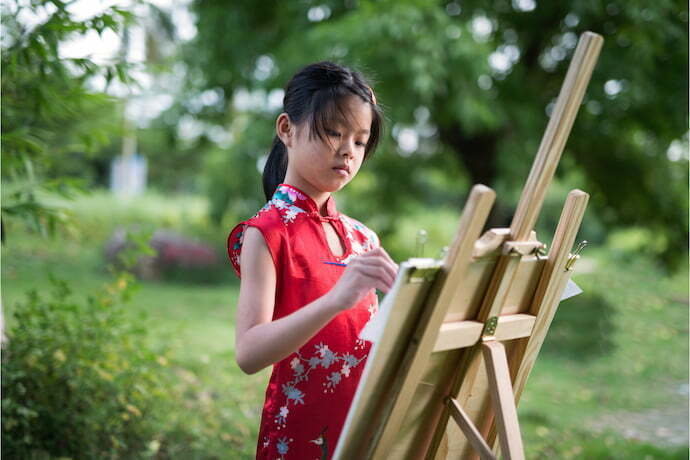 Menina pintando na tela com cavalete