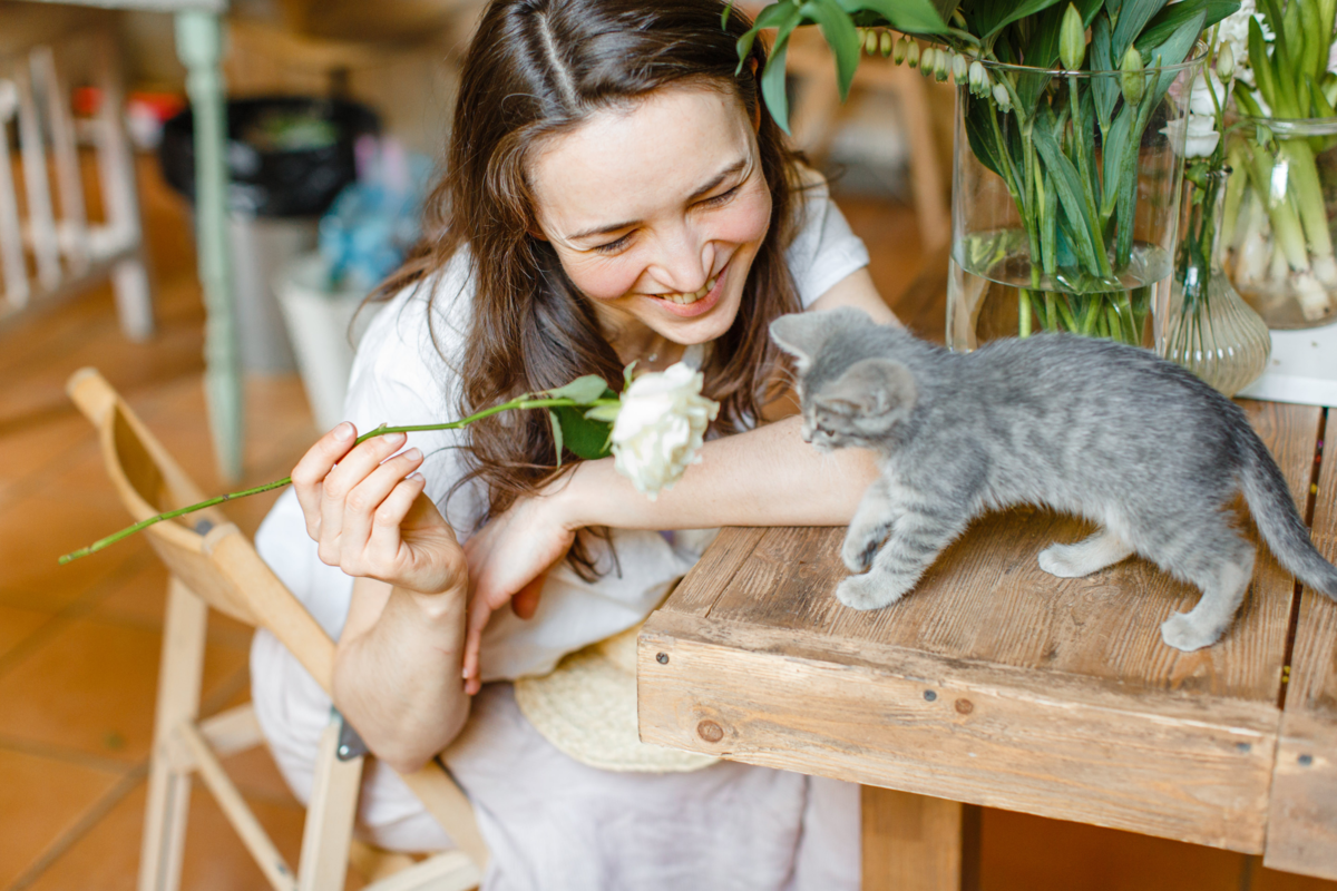 Mulher brincando com seu gato com flor