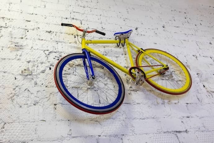 Bicicleta colorida pendurada em parede por suporte.