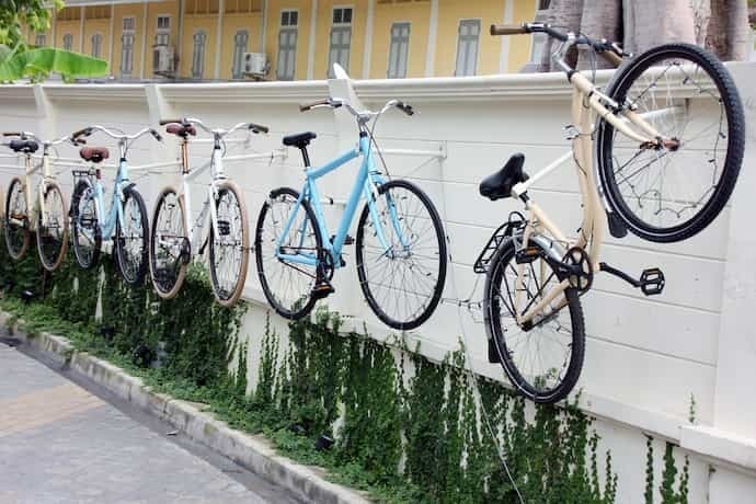 Várias bicicletas penduradas em parede por suporte.