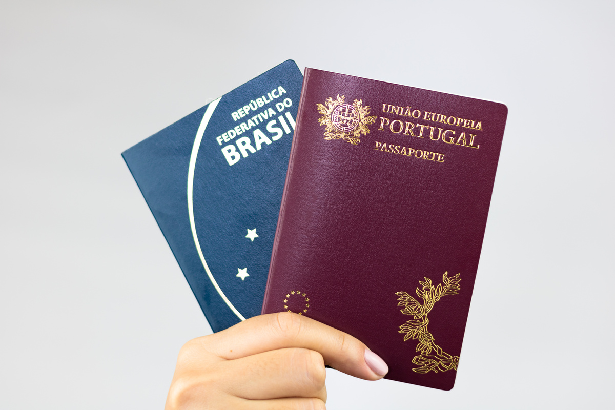 Como morar em Portugal: passaportes brasileiro e português na mão de uma pessoa