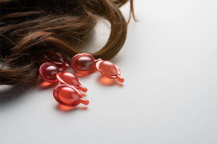 Vitaminas para queda de cabelo vermelhas ao lado de cabelo castanho.