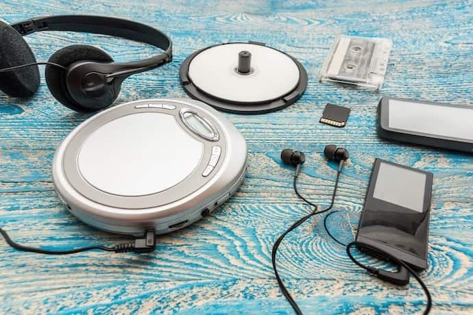 CD player portátil em fundo branco com fone ao lado em cima de tapete colorido