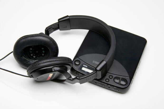 CD player portátil em fundo branco com headset ao lado