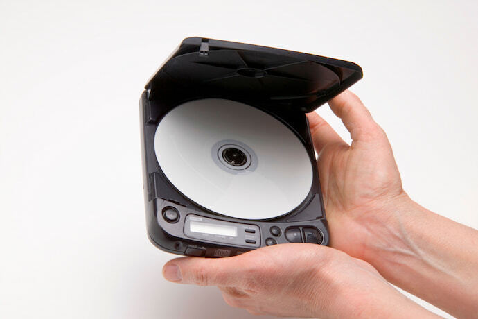 Mão segurando um CD player portátil em fundo branco