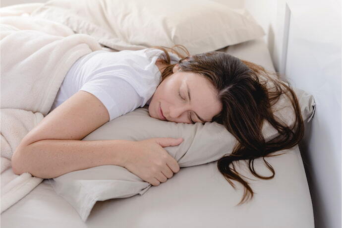 Mulher dormindo em travesseiro cervical.