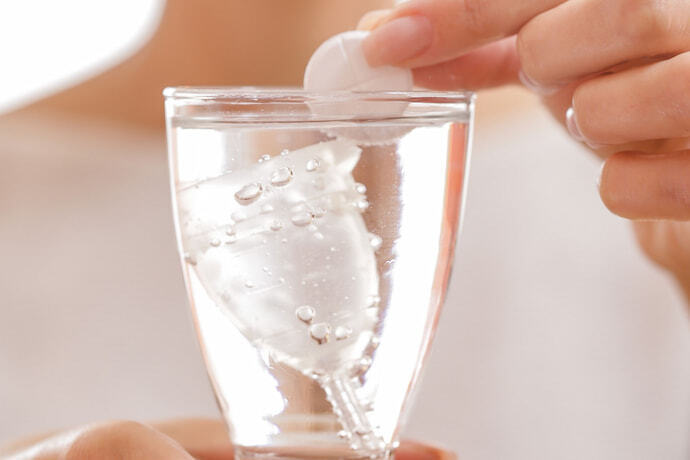 Coletor menstrual em copo de água.