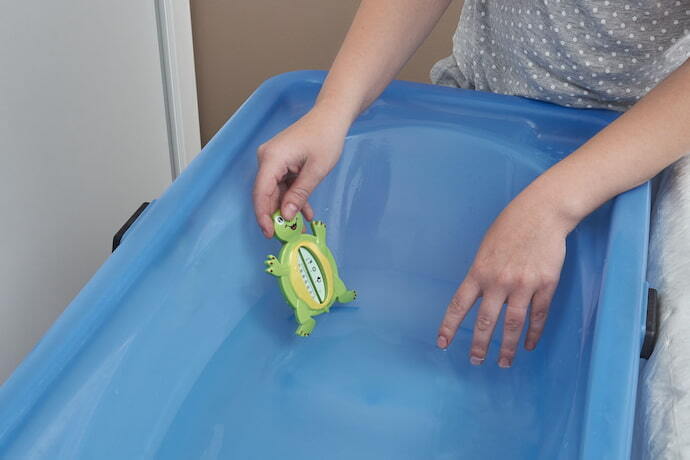 Mulher segurando termômetro de banheira em formato de tartaruga.