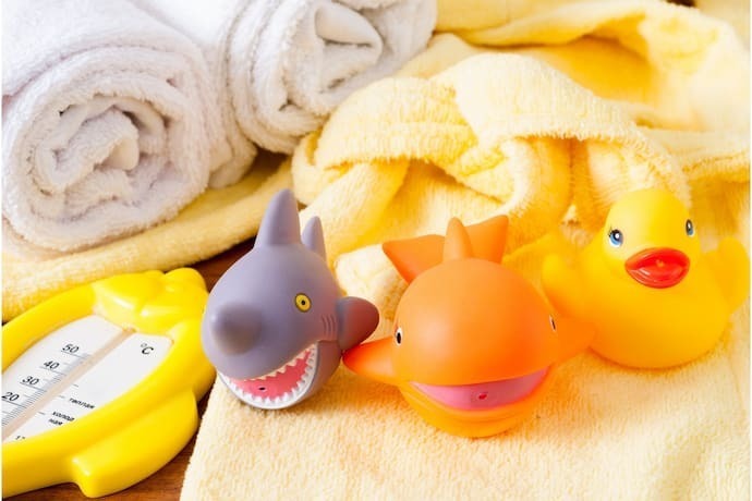 Termômetro de banheira em formato de peixe amarelo ao lado de brinquedos.