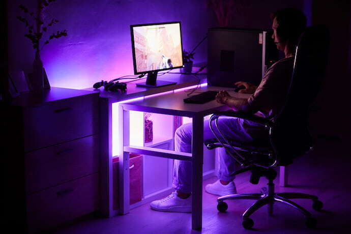 Mesa gamer branca com luz colorida ao fundo.