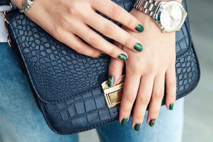 Mulher com unhas verdes segurando uma bolsa