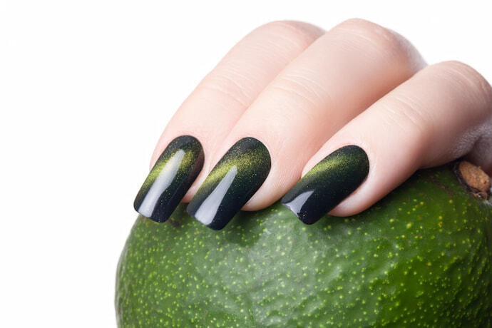 Unhas pintadas de verdes e segurando uma fruta verde