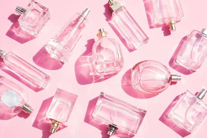 Perfumes em cima de superfície rosa
