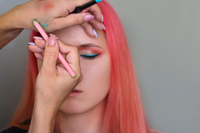 Mulher de cabelo rosa sendo maquiada