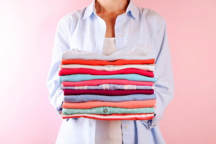 Mulher segurando pilha de roupas limpas. 