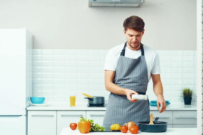 Homem usando avental de cozinha e cozinhando.