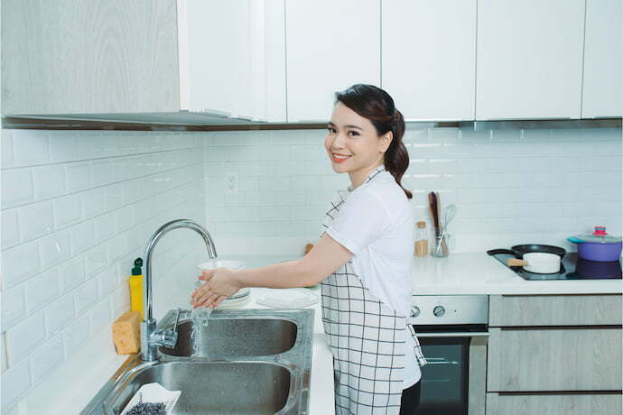 Mulher lavando as mãos usando avental de cozinha.