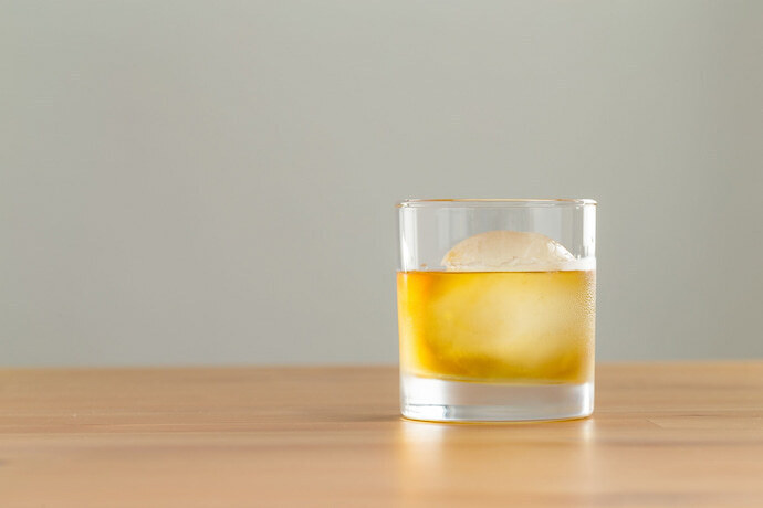 Copo de whisky com pedra de gelo grande.