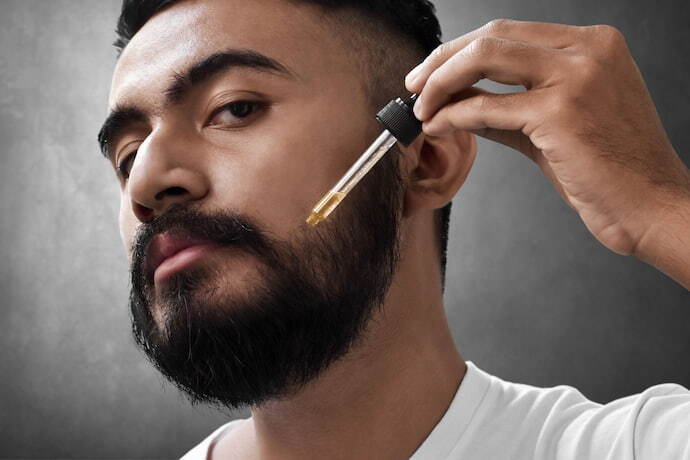 Homem aplicando óleo em barba.