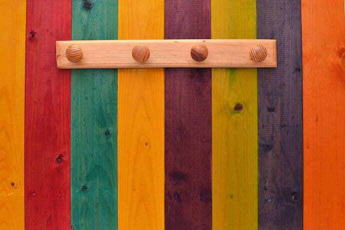 Arara de parede em madeira com parede colorida.