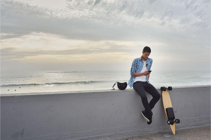 Homem sentando com skate elétrico de controle remoto.