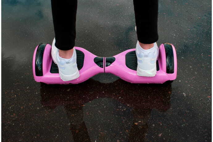 Menina andando em skate elétrico hoverboard rosa.