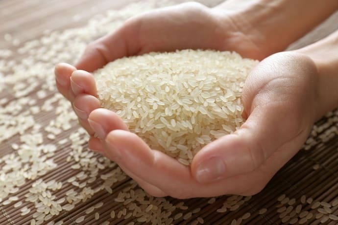 Pessoa segurando punhado de arroz parboilizado.