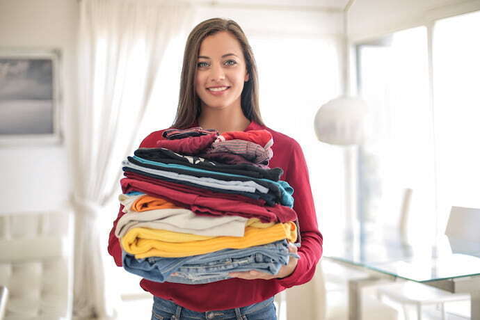 Mulher segurando roupas coloridas lavadas.