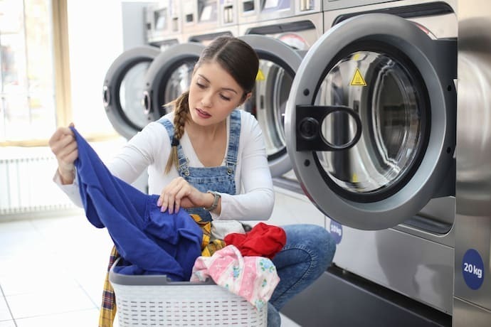 Mulher lavando roupa colorida.