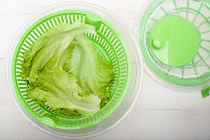 Secador de salada verde com tampa ao lado.
