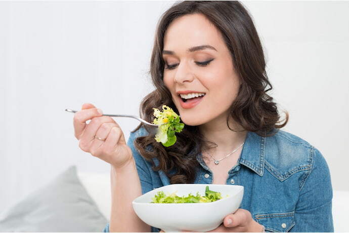 Mulher comendo salada. 