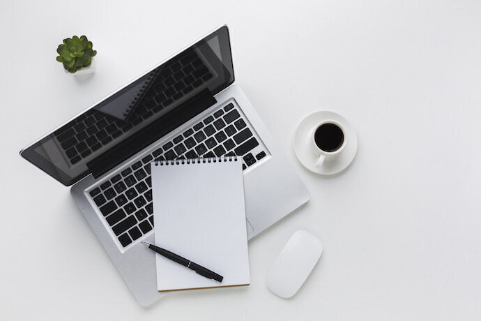 Notebook com folha em cima do teclado e itens de escritório.
