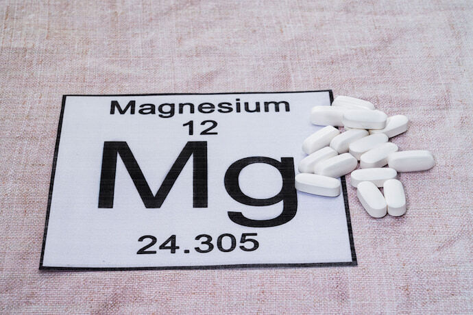 Placa com símbolo do magnésio e alguns comprimidos 