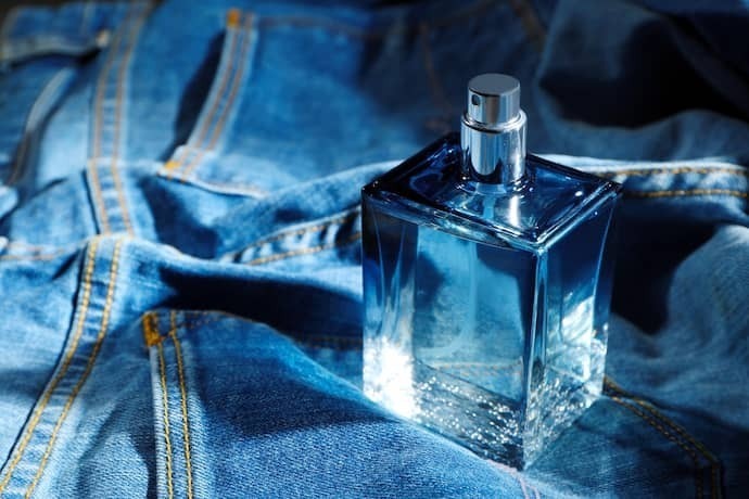Perfume masculino em cima de jeans.