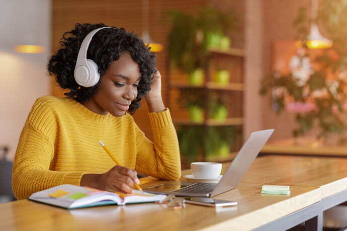 Mulher com fone de ouvido estudando em notebook.