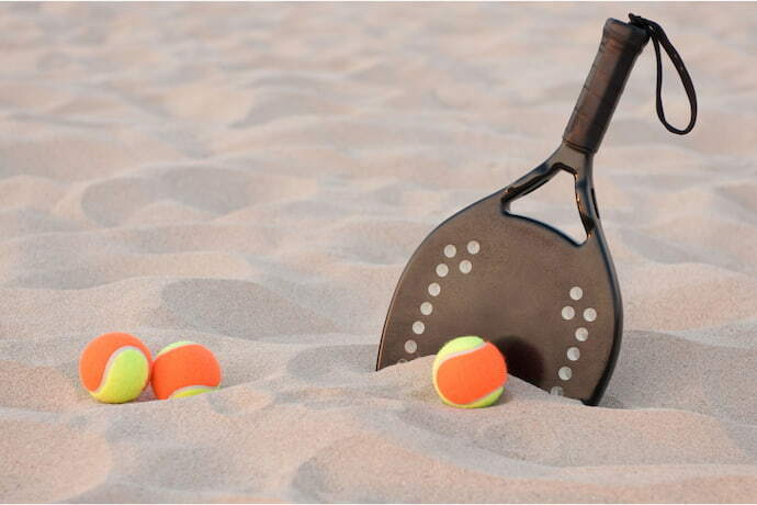 Raquete de Beach Tennis preta com bolinhas laranja.