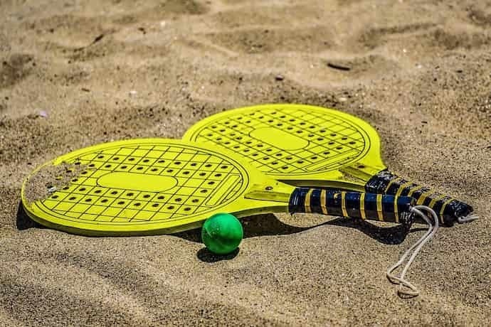 Duas raquete de Beach Tennis amarelas em areia.