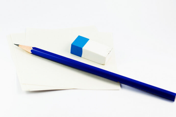 Lápis HB azul ao lado de borracha e folha