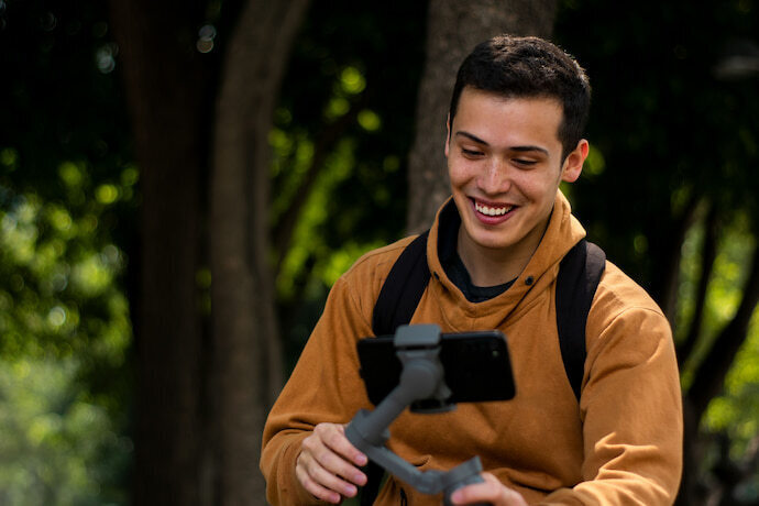 Homem segurando estabilizador de celular e sorrindo