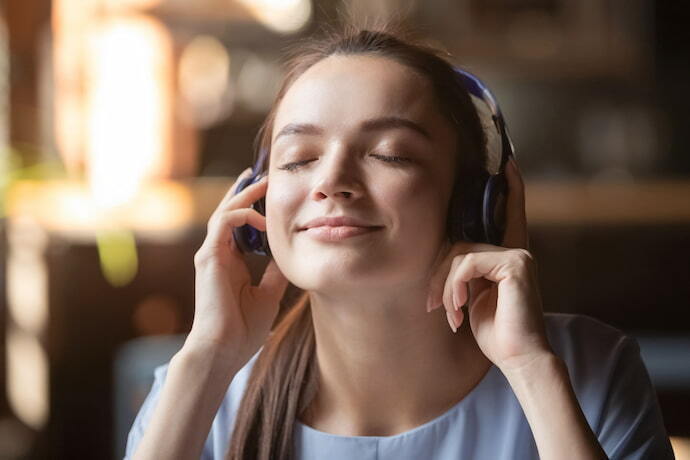 Menina feliz ouvindo música com headphone Bluetooth.