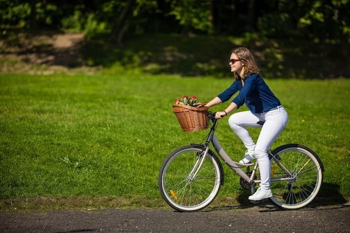 Mulher andando em bicicleta com cesto.