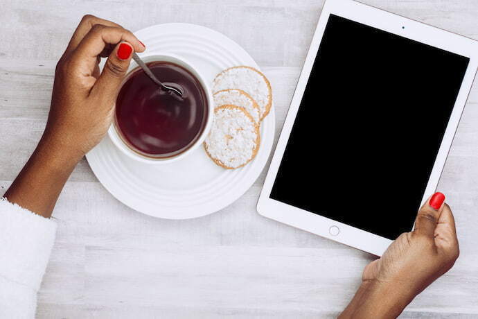 Mulher utilizando iPad e café ao lado