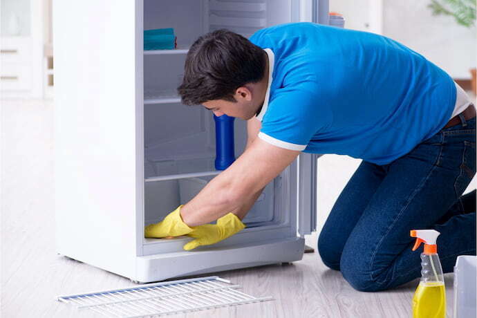 Homem limpando geladeira