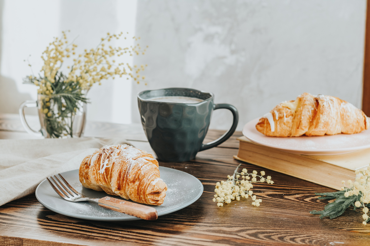 Uma mesa com uma xícara e dois croissant